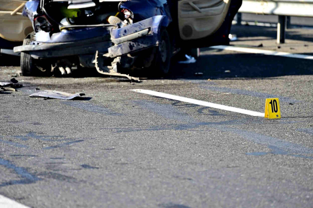 Damaged blue car and debris on a highway with an evidence marker, depicting the aftermath of a hit-and-run accident on North Carolina’s highways.