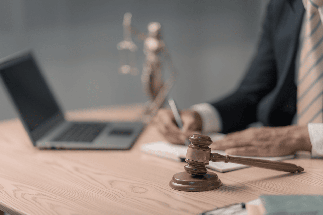 The lawyer, dressed in a suit, is writing in a notebook while holding a pen.